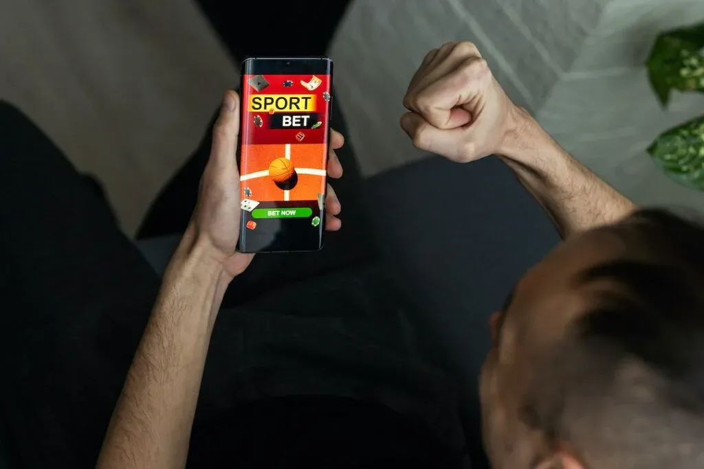 Person holding a phone displaying a sports betting app.